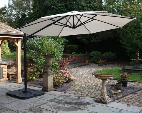 Large cream cantilever garden parasol with black frame on patio next to landscaped garden