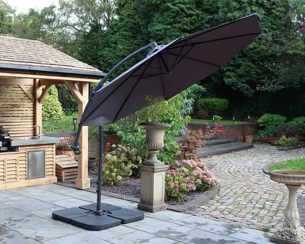 Grey cantilever garden parasol with base on patio beside outdoor kitchen