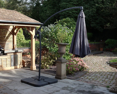 Grey cantilever garden parasol with base on stone patio beside outdoor kitchen