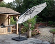 White cantilever garden parasol with black base on stone patio beside outdoor kitchen