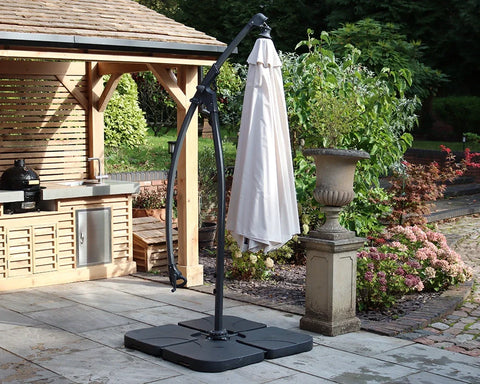 Beige outdoor cantilever parasol with black base on patio beside wooden garden gazebo