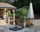 Cantilever patio parasol with closed cream canopy on tiled garden terrace