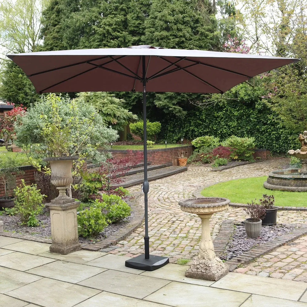 Brown garden parasol with black pole on patio in landscaped outdoor setting
