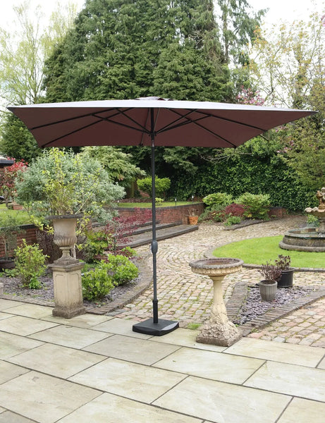Brown garden parasol with black pole on patio in landscaped outdoor setting