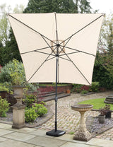 Beige garden parasol with black pole and square base on stone patio