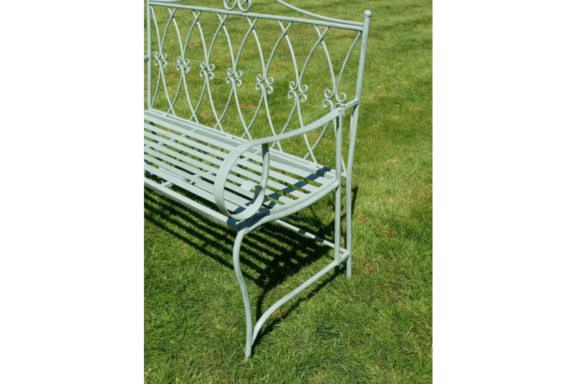 Light green metal garden bench with decorative backrest on grass lawn