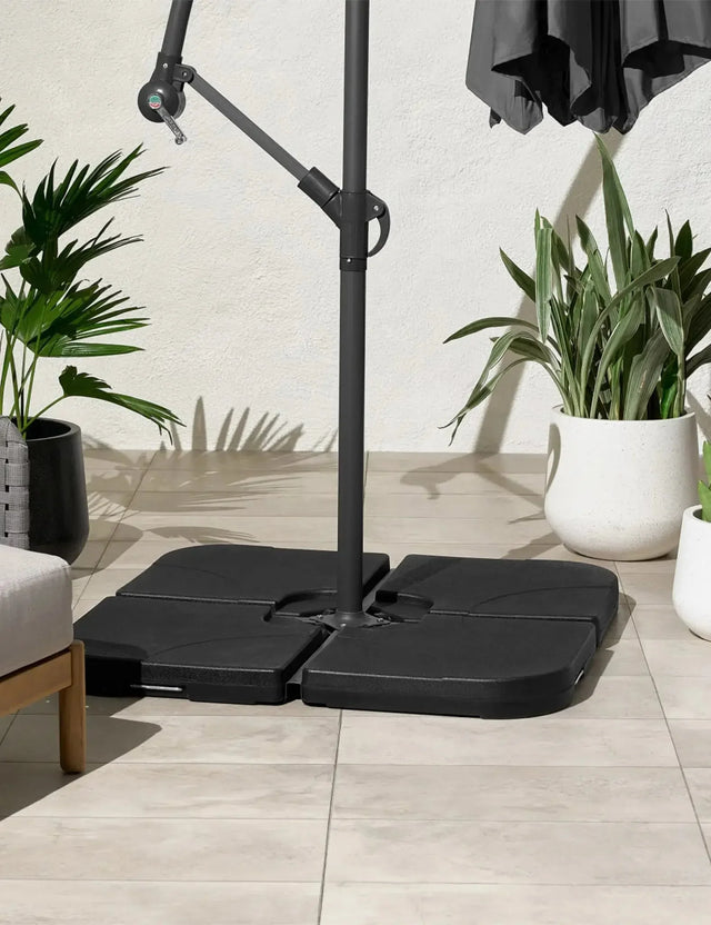 Garden parasol base set on tiled patio beside potted plants and outdoor furniture