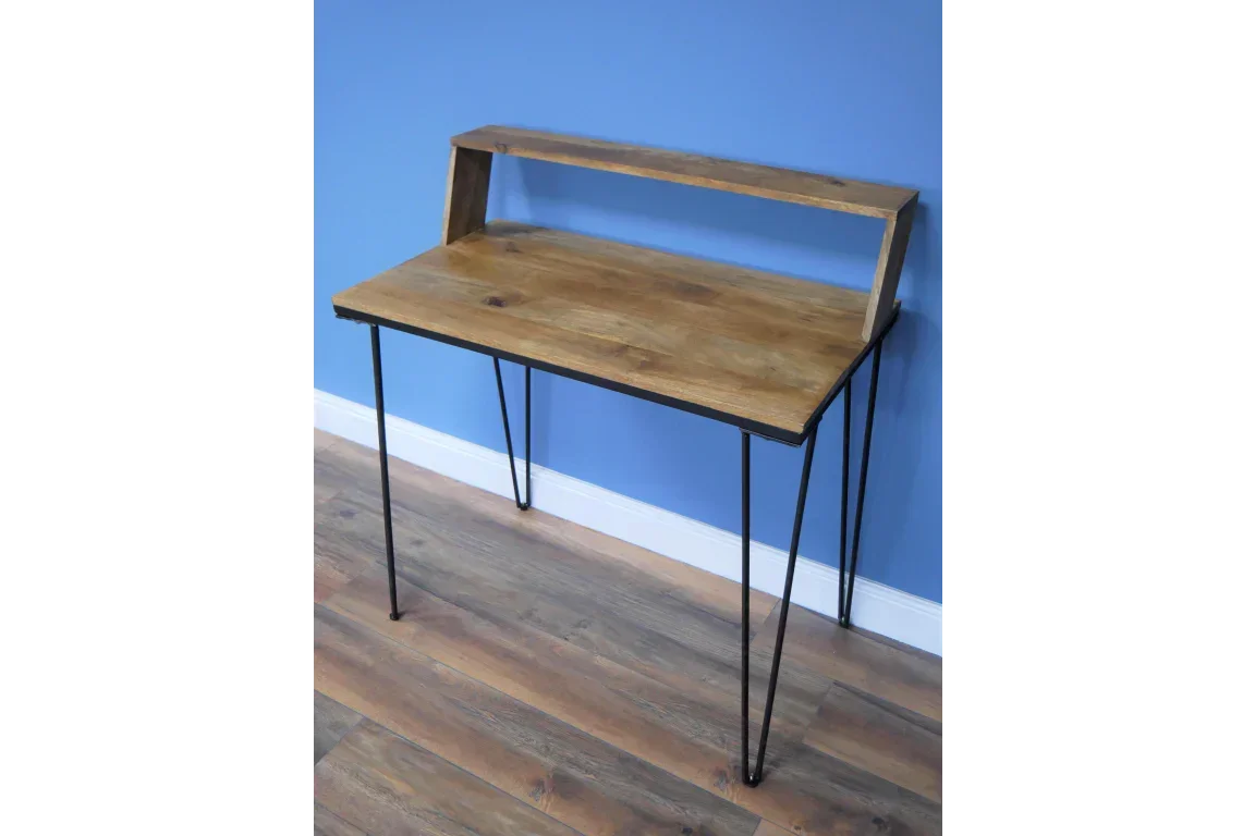 Wooden desk with black hairpin legs and raised shelf against blue wall on wood floor