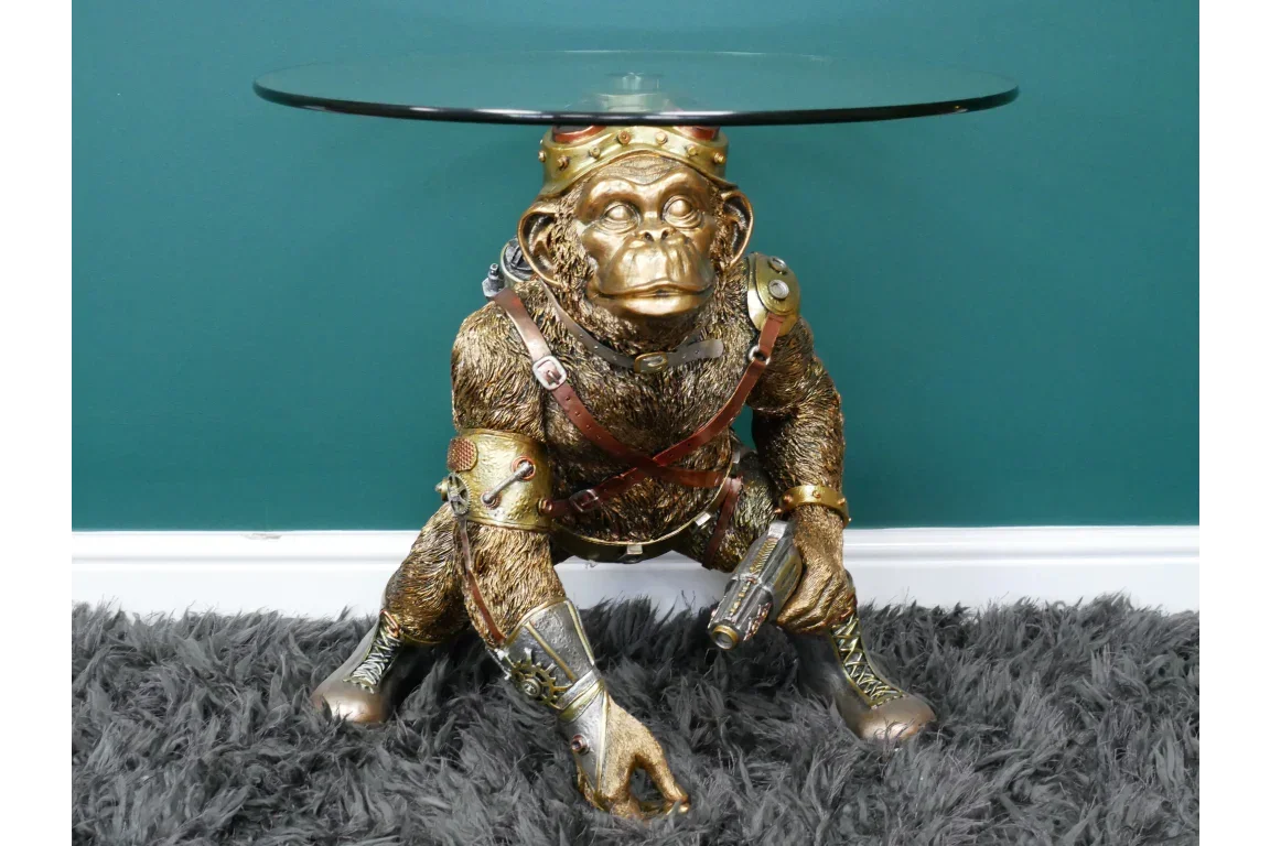 Steampunk monkey side table with round glass top and gold finish on grey rug