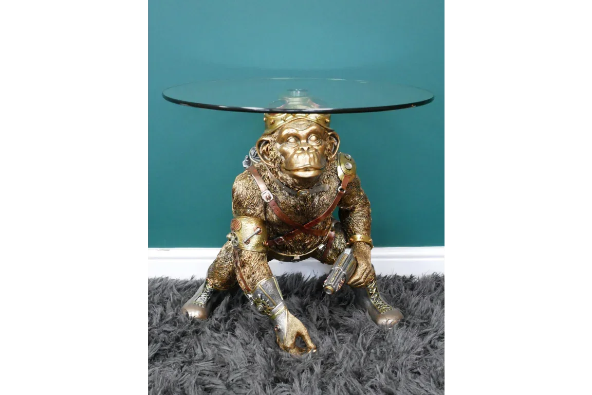 Gold monkey side table with round glass top and detailed sculpted base on grey rug
