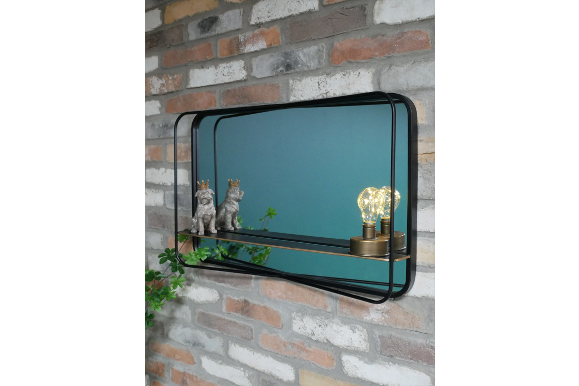 Rectangular wall mirror with black metal frame and built-in shelf, mounted on exposed brick wall, side angle view.