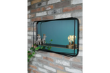Rectangular wall mirror with black metal frame and built-in shelf, mounted on exposed brick wall, side angle view.
