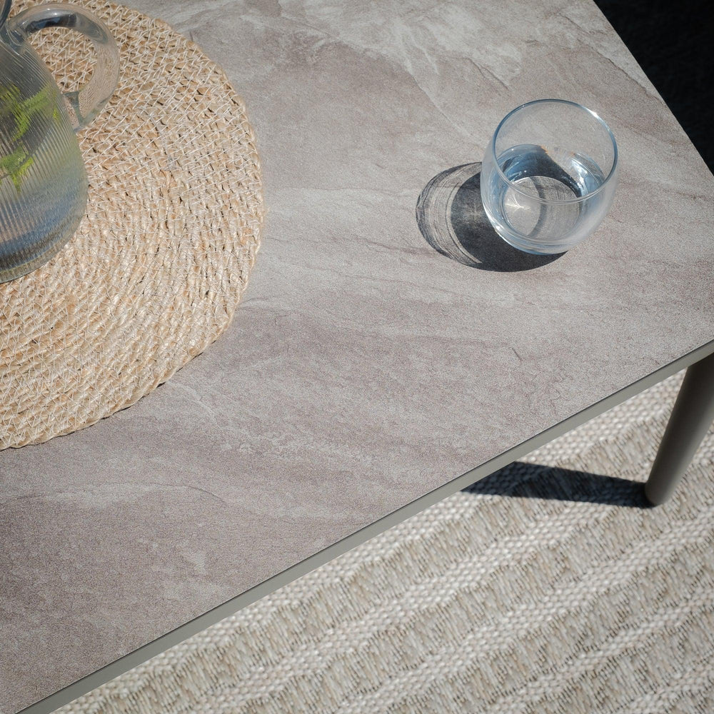 Stone effect dining table top with glass and woven table mat, angled view