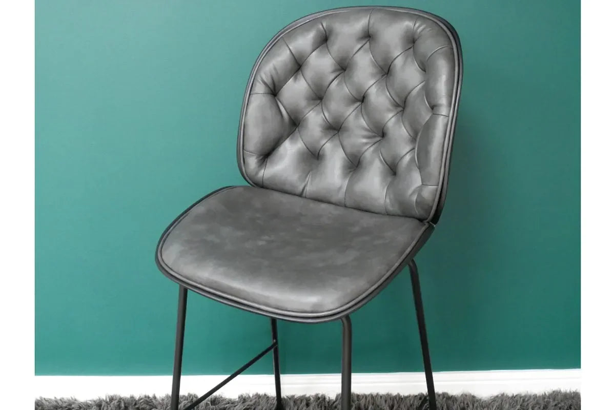 Grey faux leather dining chair with button-tufted backrest and black metal legs