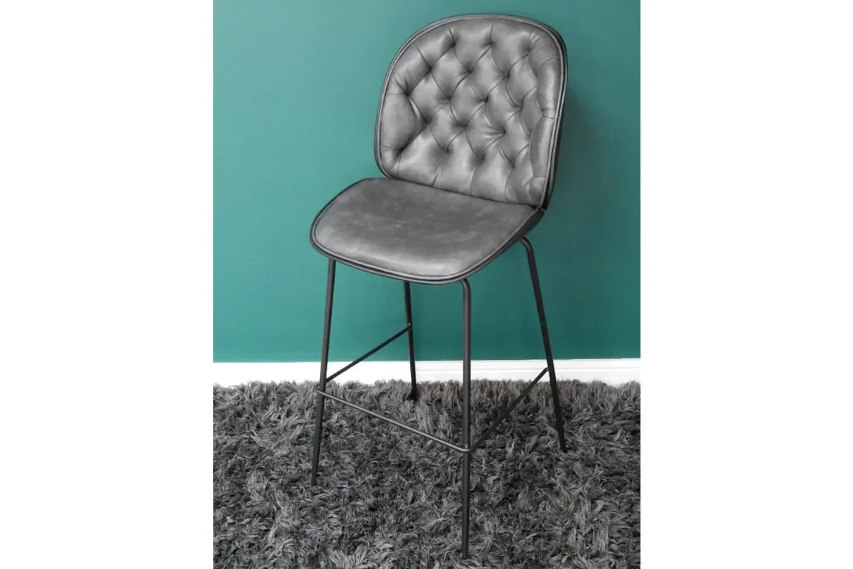 Grey leather bar stool with tufted backrest and black metal legs on shaggy rug