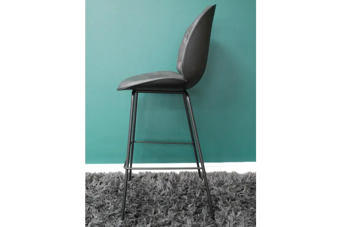 Grey faux leather bar stool with metal legs on grey rug against teal wall