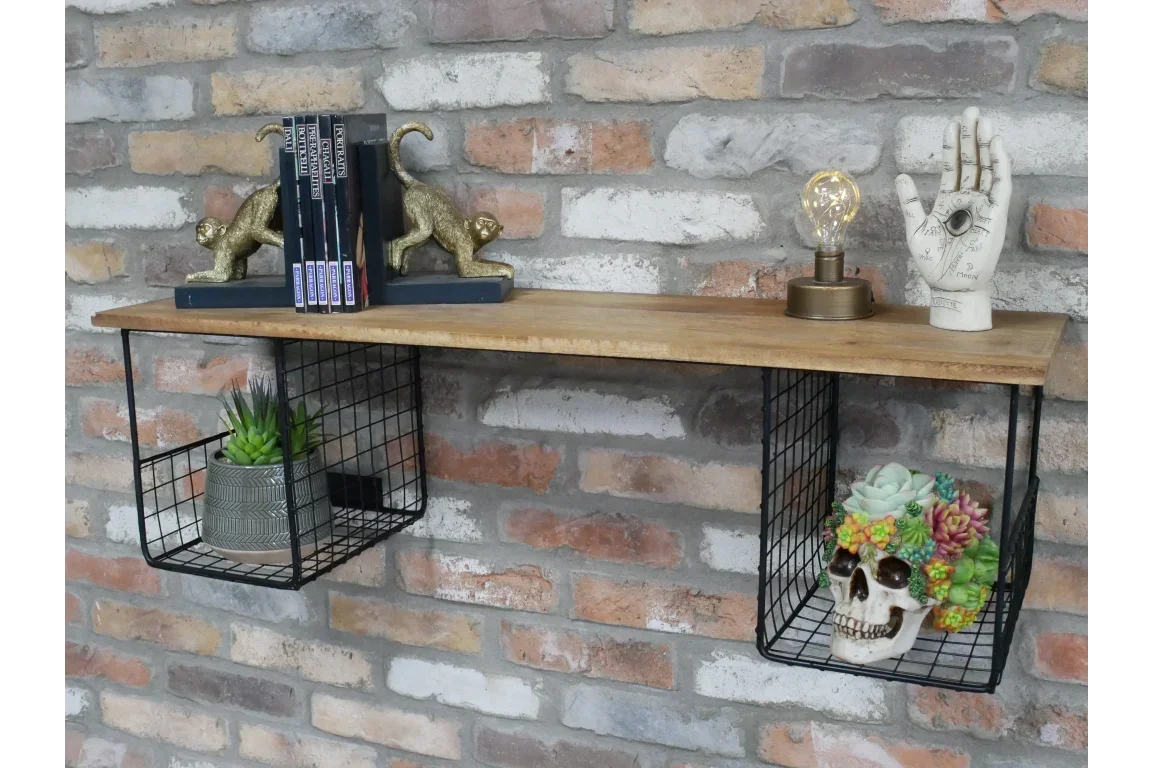 Wooden wall shelf with black wire storage baskets, books and decorative items against brick wall