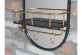 Round black-framed mirror with black shelf and gold metal railing, hooks, mounted on a brick wall, angled view.