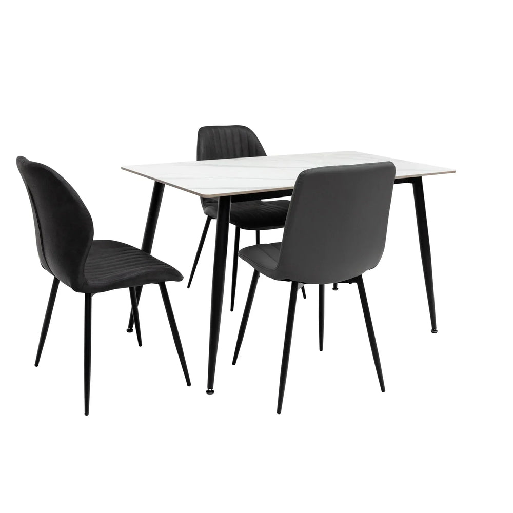 Modern dining table with white top and three black upholstered chairs on black metal legs