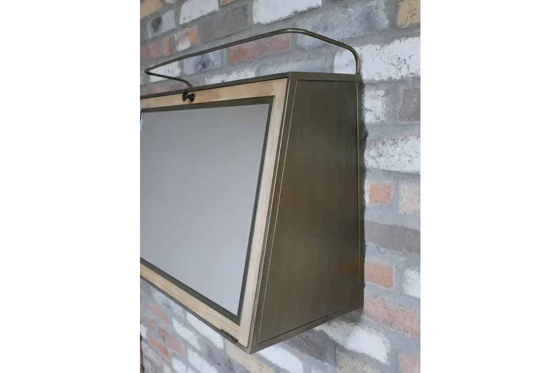 Wall-mounted mirror cabinet with brass frame and angled side on brick wall