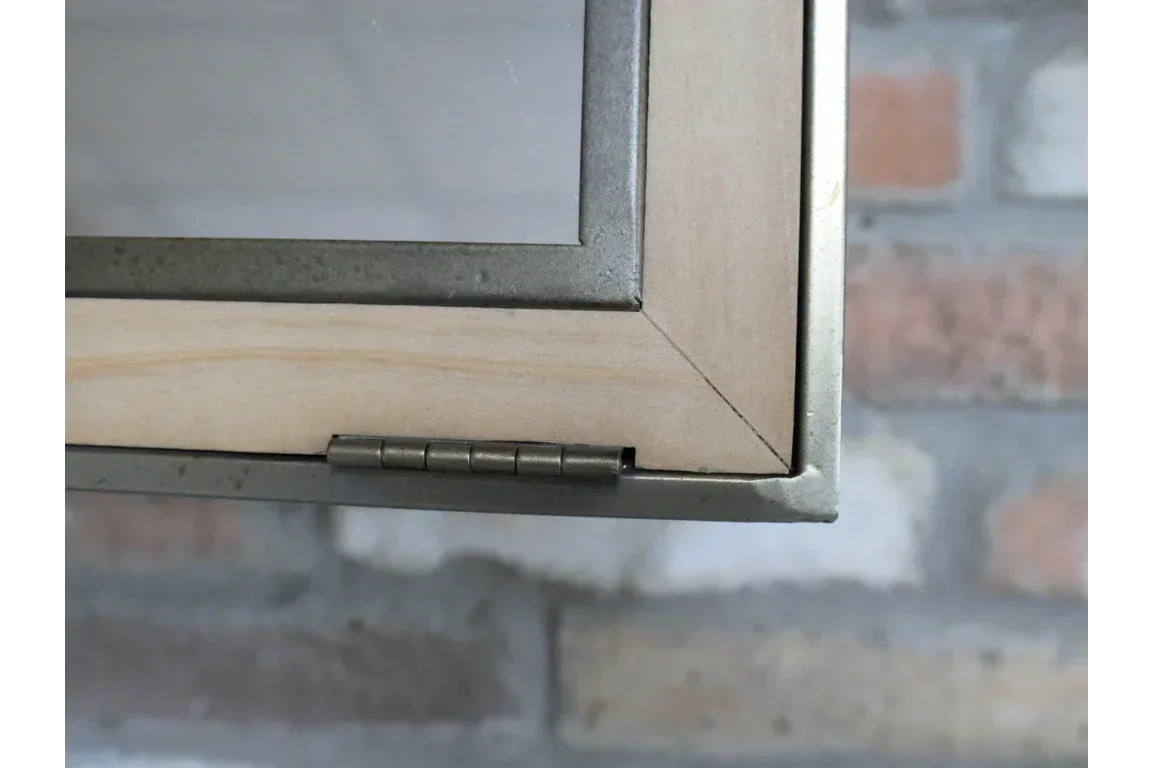 Close-up of cabinet door hinge and wood frame against brick wall background