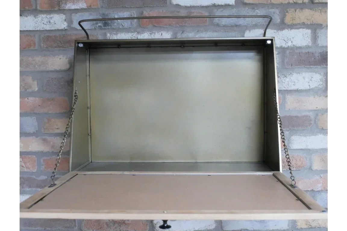 Wall-mounted metal folding desk with chains and storage compartment against brick wall