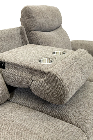 Close-up of a gray upholstered recliner chair with a center armrest featuring two cup holders and a power control switch, set against a plain white background.