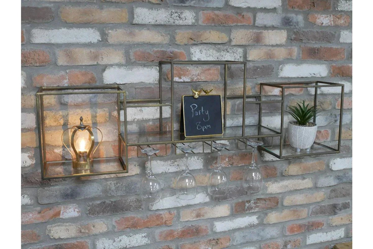 Brass wall mounted wine glass rack with light, chalkboard sign, and potted plant against brick