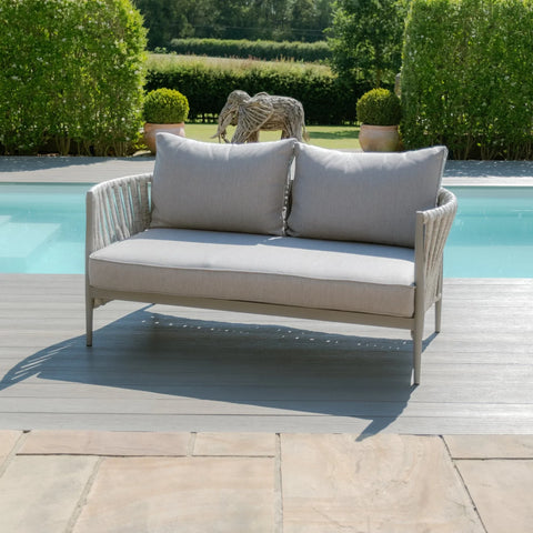 Light grey outdoor sofa with rope arms and cushions beside a pool on a patio