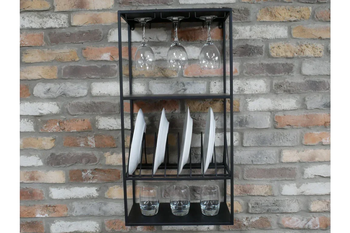 Black metal kitchen wall rack holding plates, glasses, and wine glasses against brick wall