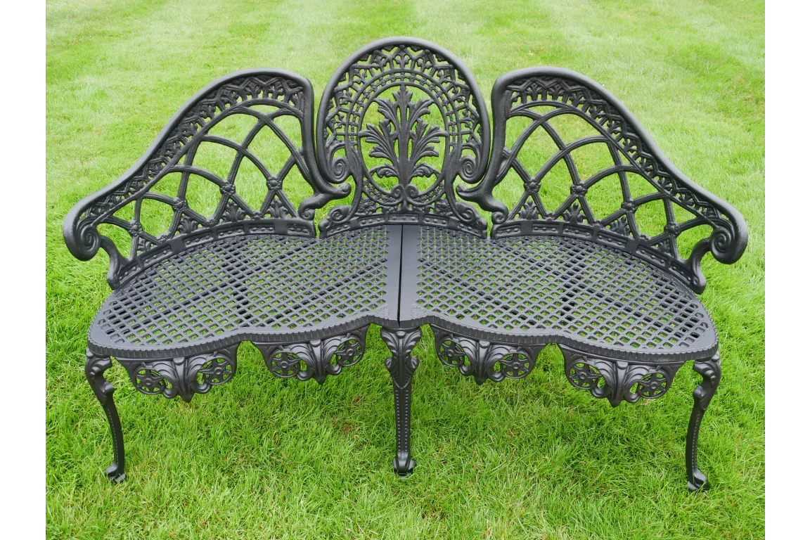 ornate black cast iron garden bench with decorative backrest on grass