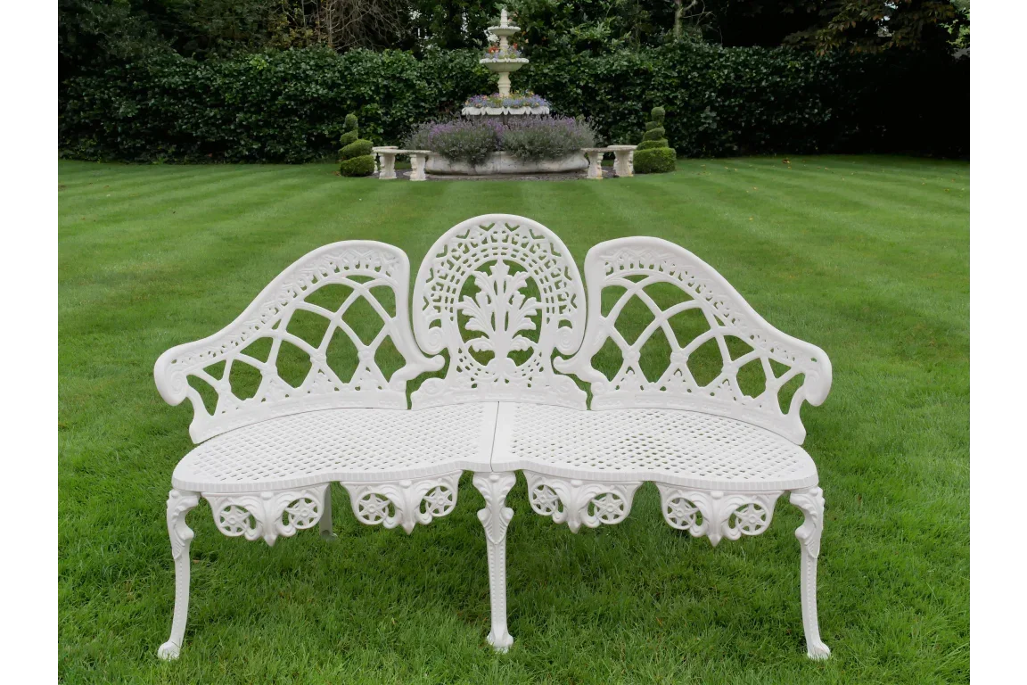 White cast iron garden bench with decorative backrest on lawn