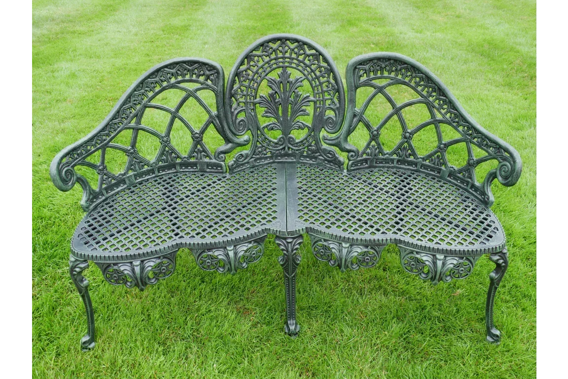Ornate cast iron garden bench with decorative backrest on grass lawn