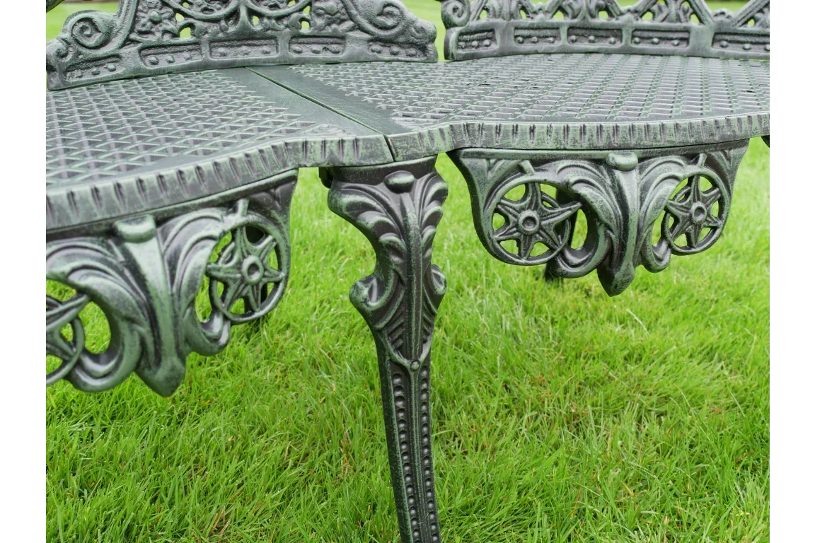 Cast iron garden bench with ornate detailing on grass lawn