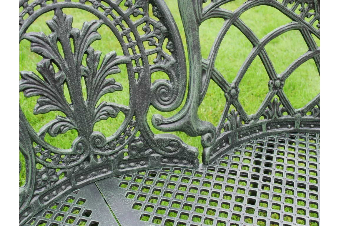 ornate metal garden bench with decorative cast iron backrest and seat on grass