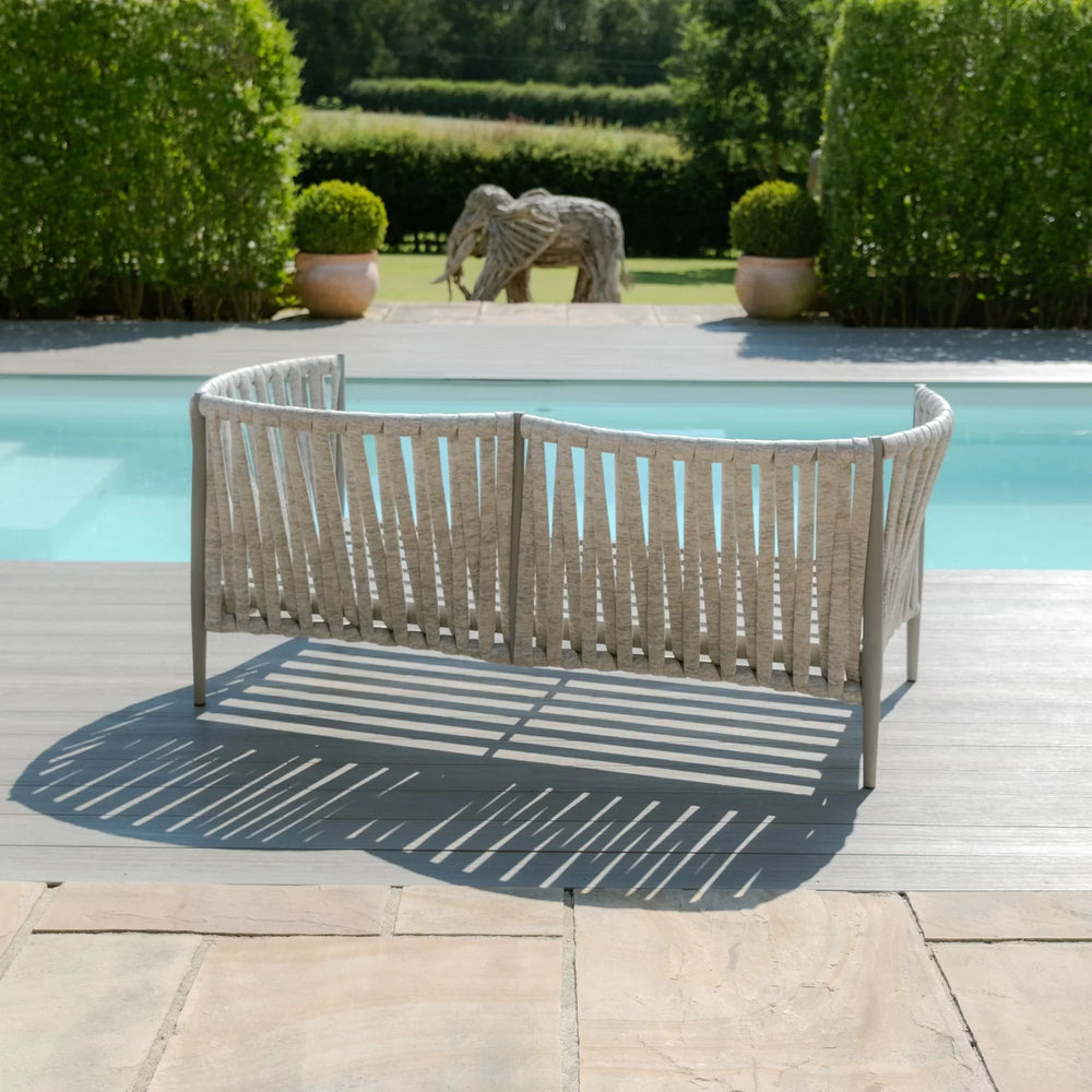 Outdoor woven rope garden sofa by swimming pool on a grey decking patio