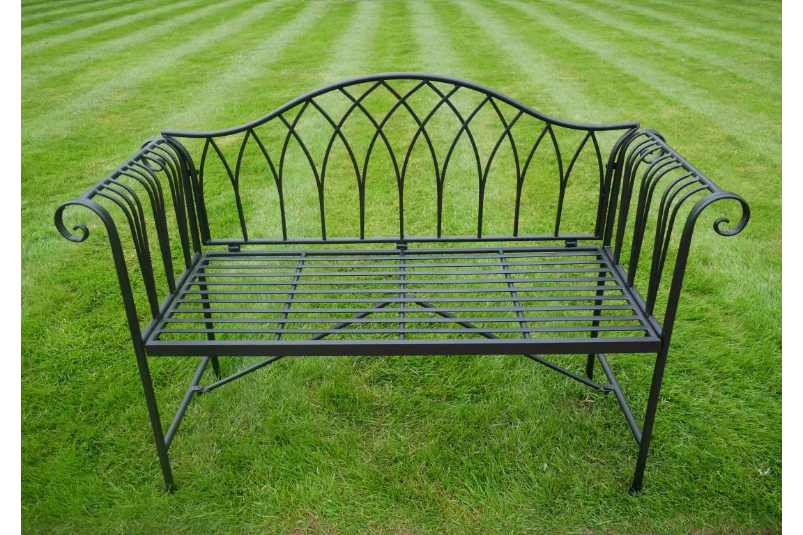 black metal garden bench with decorative backrest on grass lawn