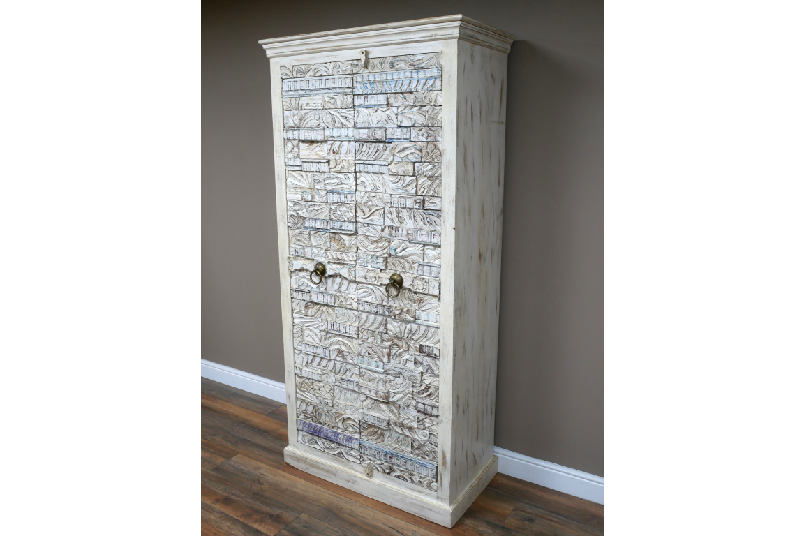 Large wooden cabinet with carved textured whitewashed doors and bronze ring handles, angled view in room.