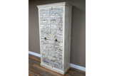 Large wooden cabinet with carved textured whitewashed doors and bronze ring handles, angled view in room.