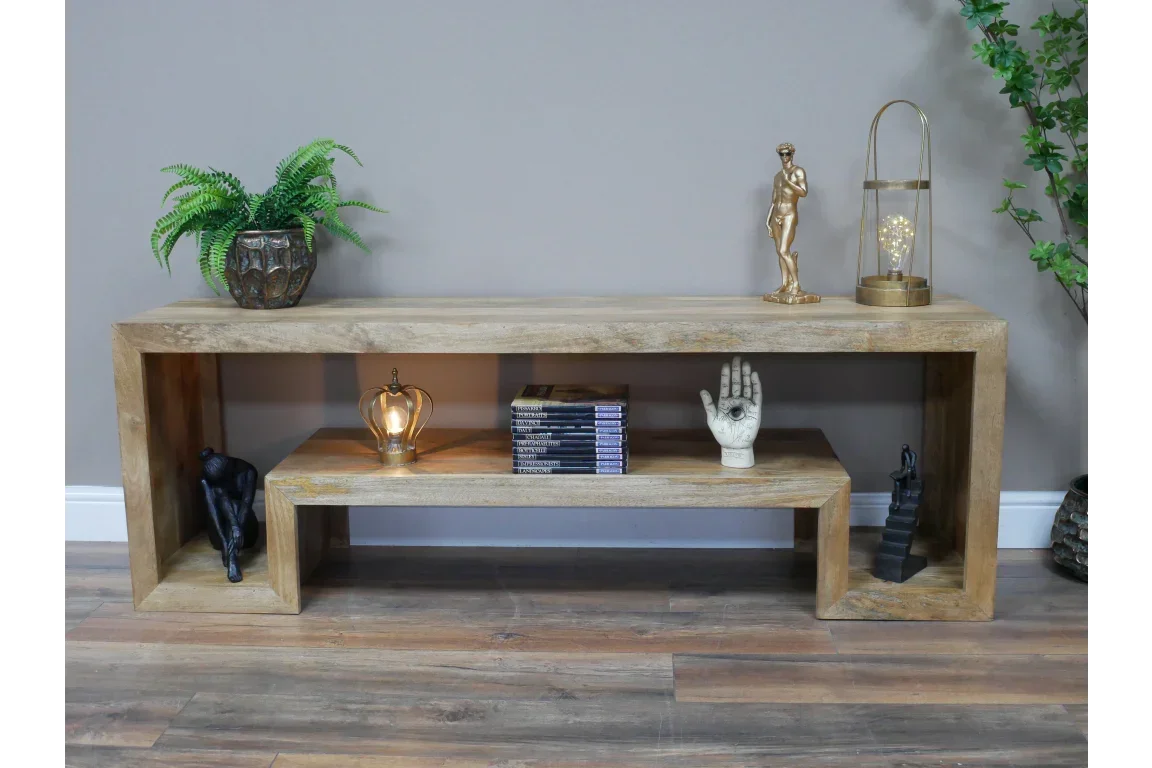 Natural wood console table with books, decorative statues, lamp, and potted plant on display