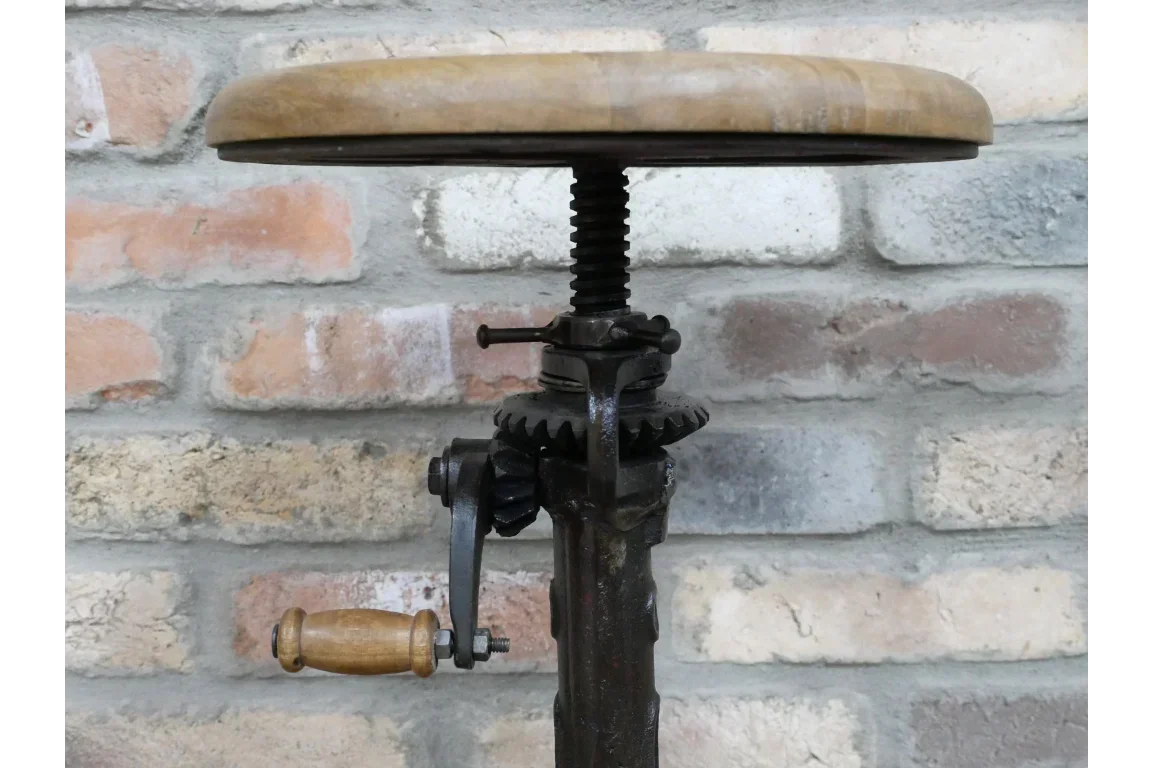 Closeup of industrial adjustable bar stool with wooden seat and metal gear base