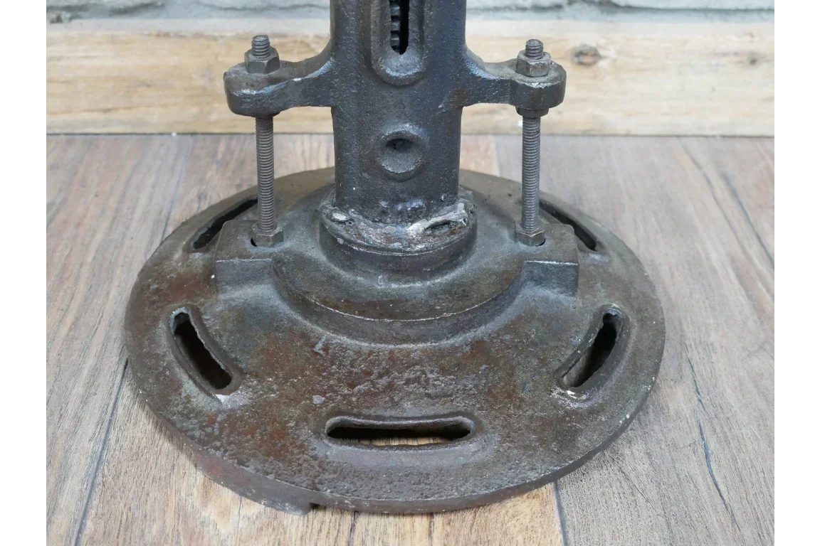 Rustic cast iron table base with bolts on wooden floor
