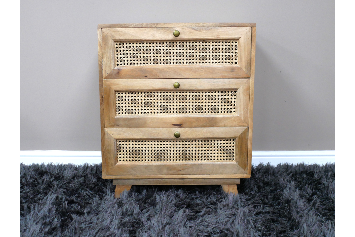 This small chest of drawers features a natural wood finish with three woven rattan front panels and round brass knobs, providing a stylish storage solution