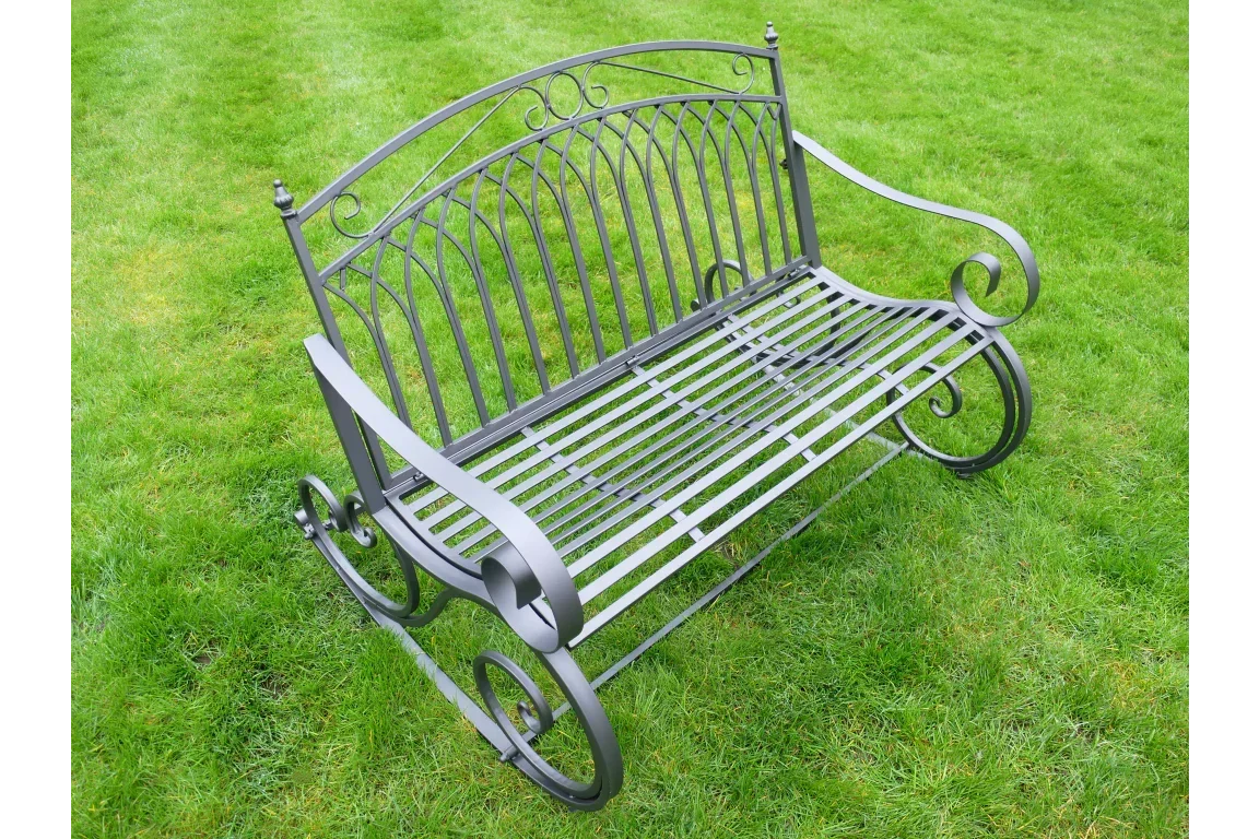 Black metal garden bench with decorative scroll armrests on green lawn