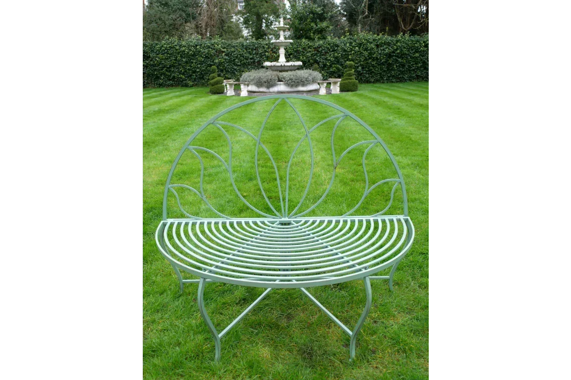 Metal garden bench with curved backrest and leaf design on lawn