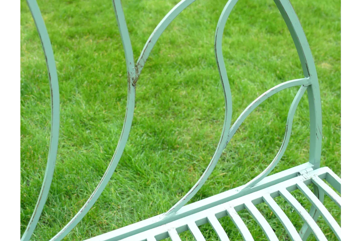 Close view of metal garden bench backrest with curved design on green grass
