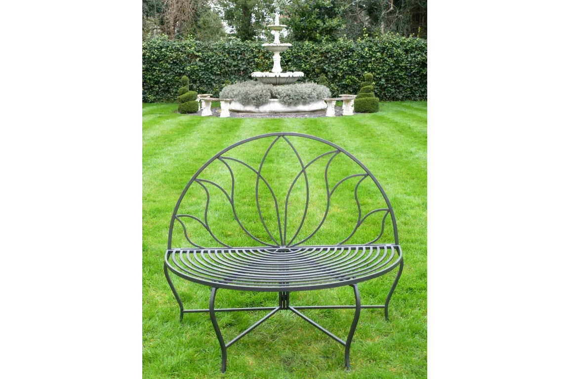 Black metal garden bench with curved backrest and decorative detailing on lawn