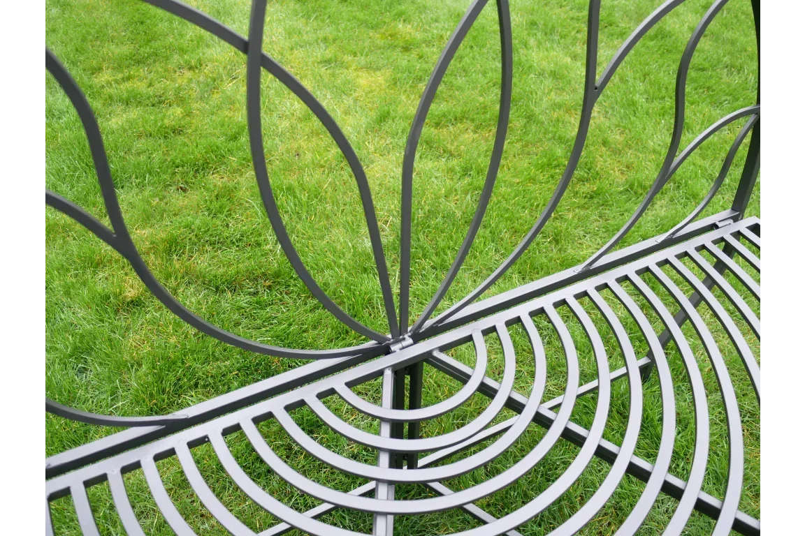 Black metal garden bench with decorative backrest design on grass lawn