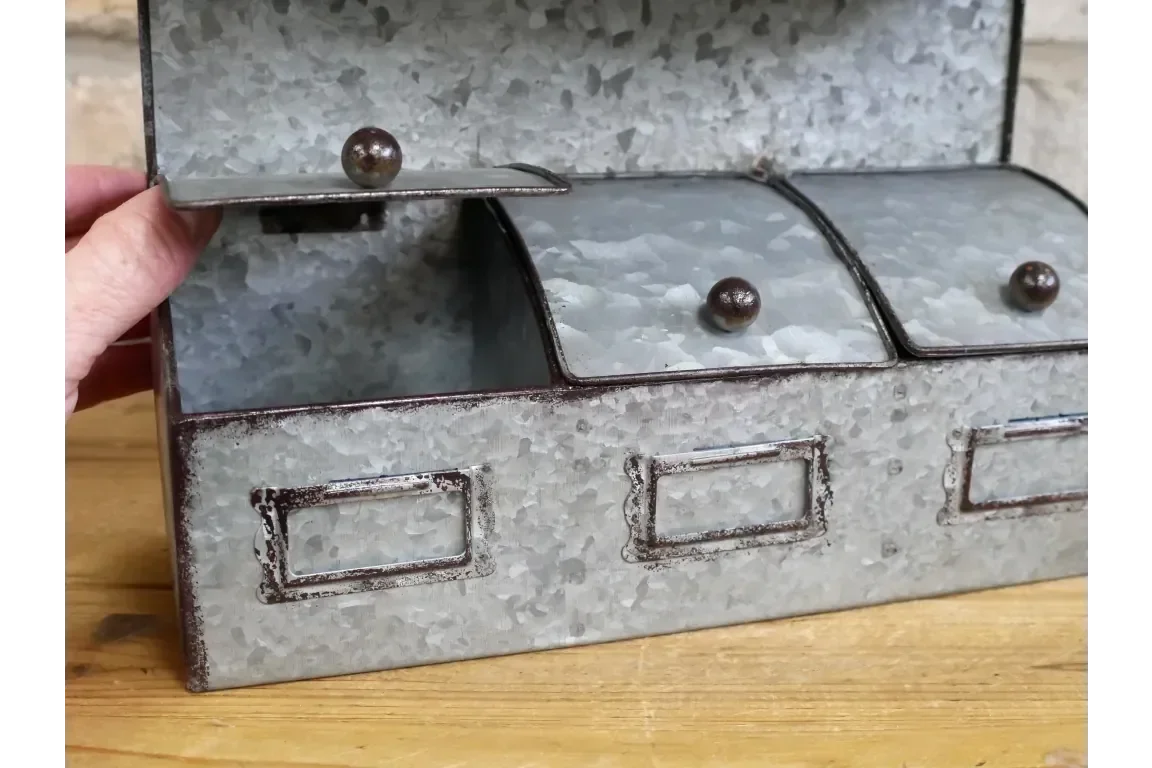 Galvanised metal storage box with three compartments and knob handles on wooden surface