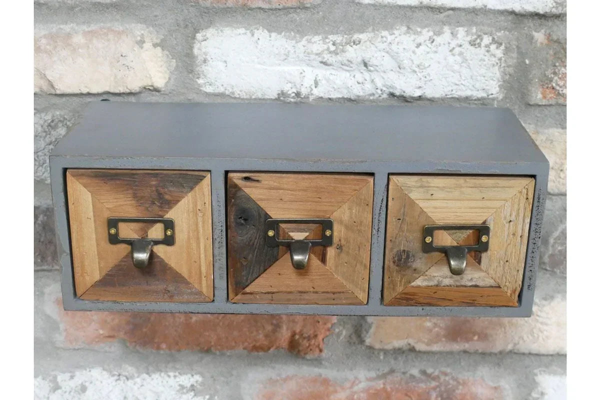 Wall mounted storage unit with three wooden drawers and metal handles on brick background